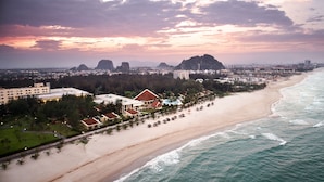 A coastal resort with beachfront villas, a sandy beach, and a view of the ocean.
