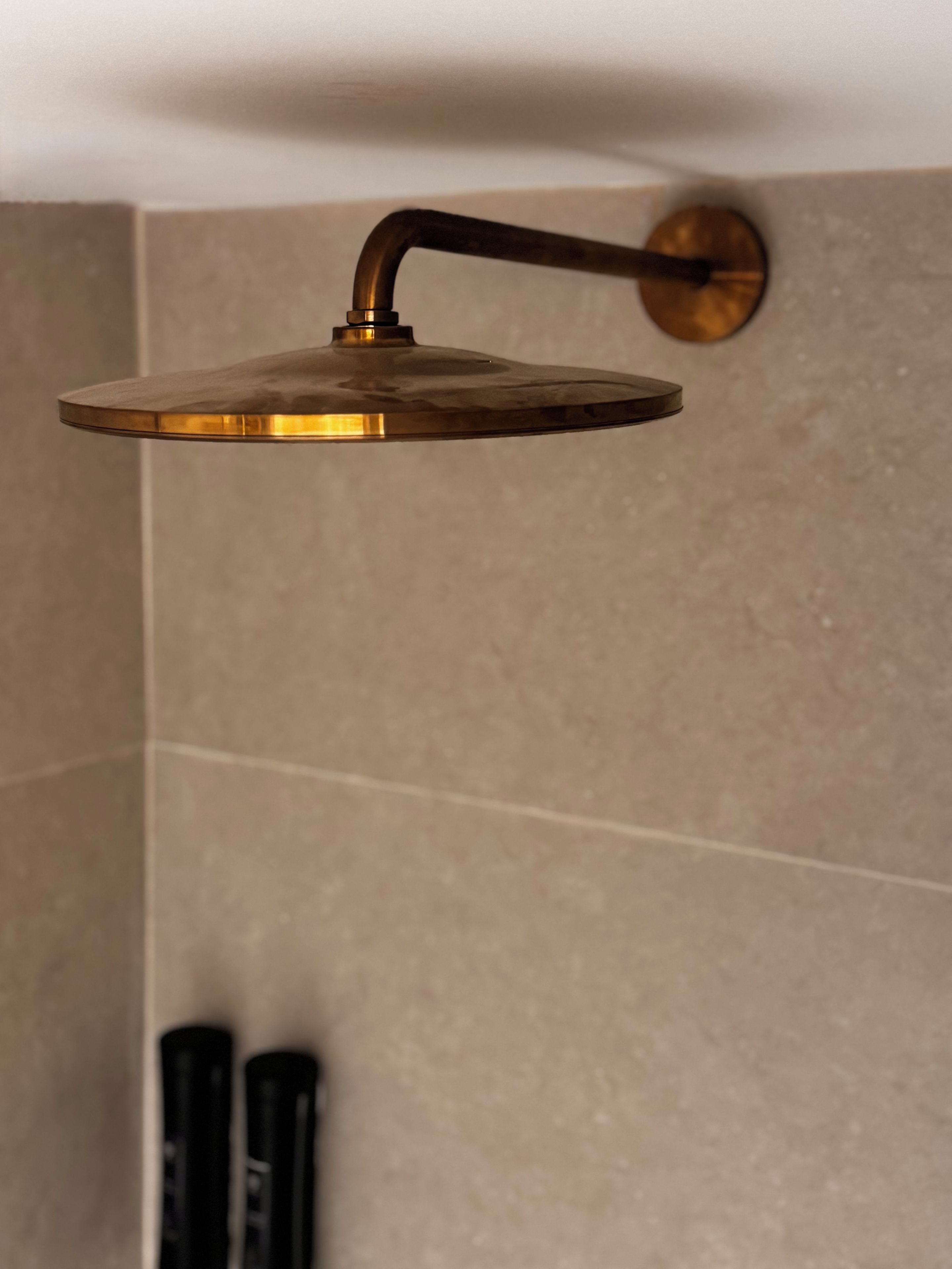 Un cabezal de ducha moderno con un diseño curvo, fijado a una pared con superficie texturizada.