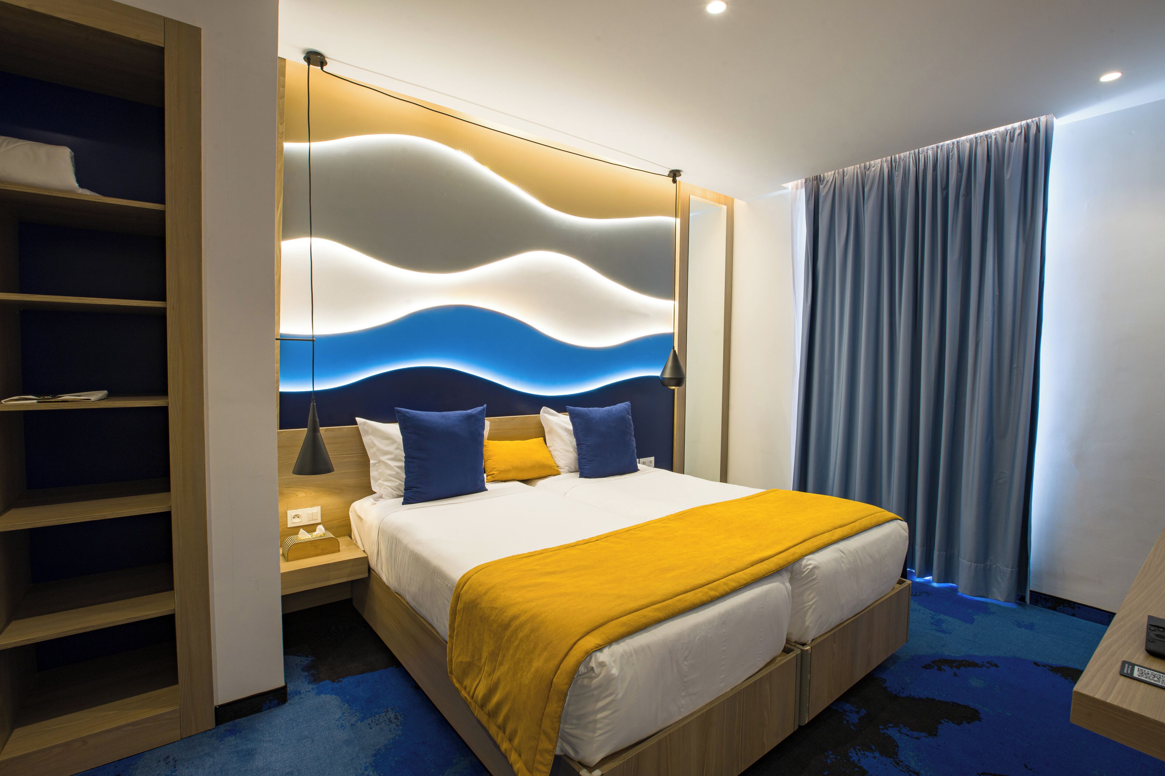 A hotel room with a bed, bedside tables, a wardrobe, and a view of the outside.
