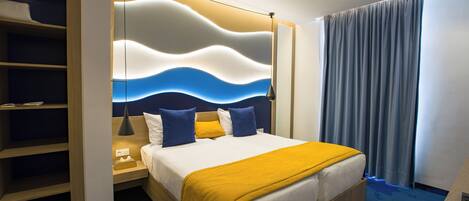 A hotel room with a bed, bedside tables, a wardrobe, and a view of the outside.