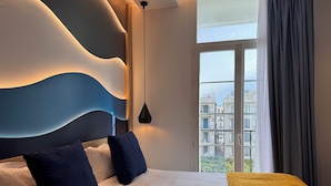Habitación de hotel moderna con una cama grande, vista a la ciudad a través del ventanal y un diseño de pared original.