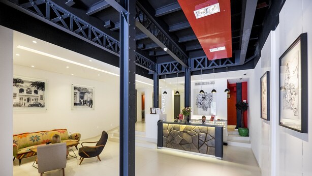 Un interior moderno con un mostrador de recepción, zona de estar y obras de arte en las paredes.