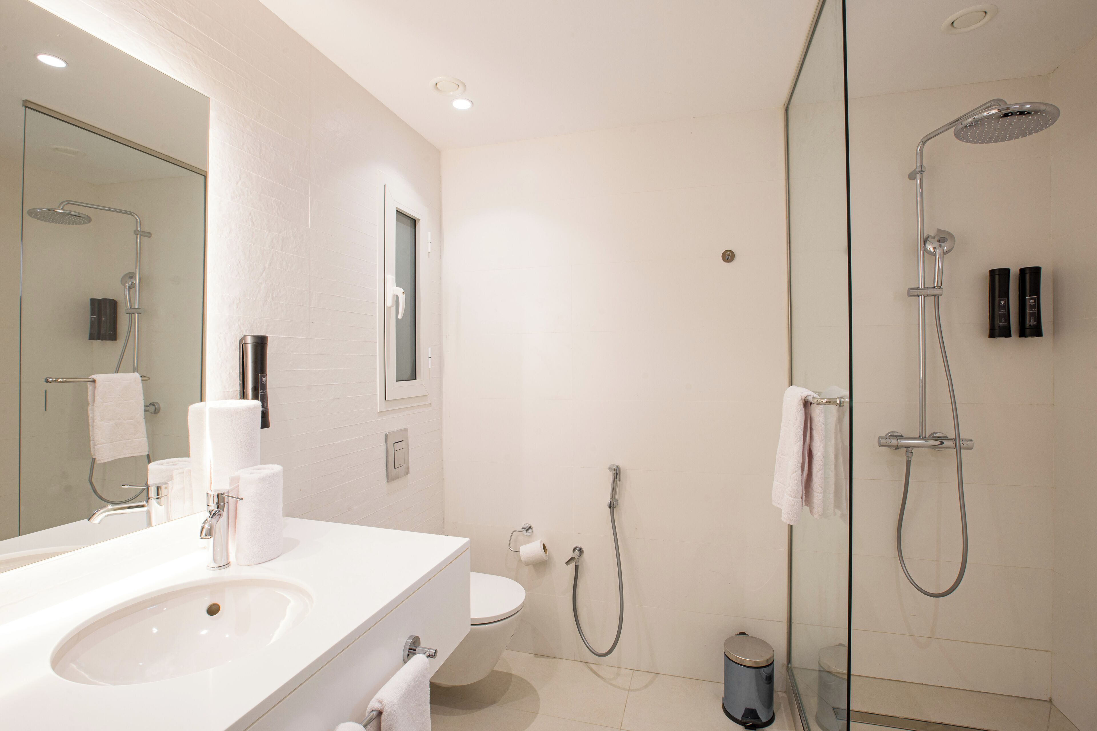 Een moderne badkamer met een wastafel, toilet en douchecabine met glazen wanden.