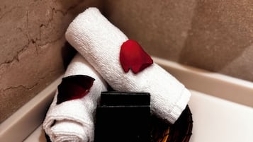 A corner of a room with a white towel and a red rose placed on a black object, possibly a tray or a small table.