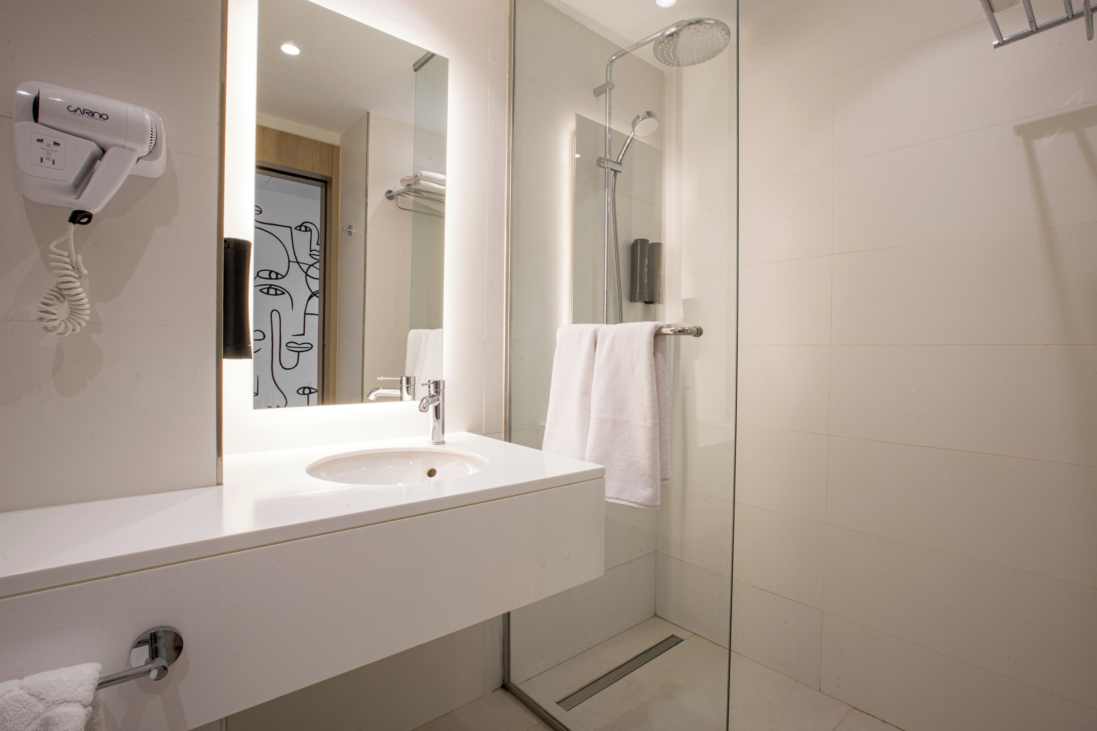 Un baño moderno con lavamanos, espejo y ducha.