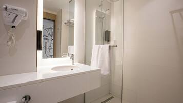 Un baño moderno con lavamanos, espejo y ducha.