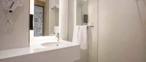 Un baño moderno con lavamanos, espejo y ducha.