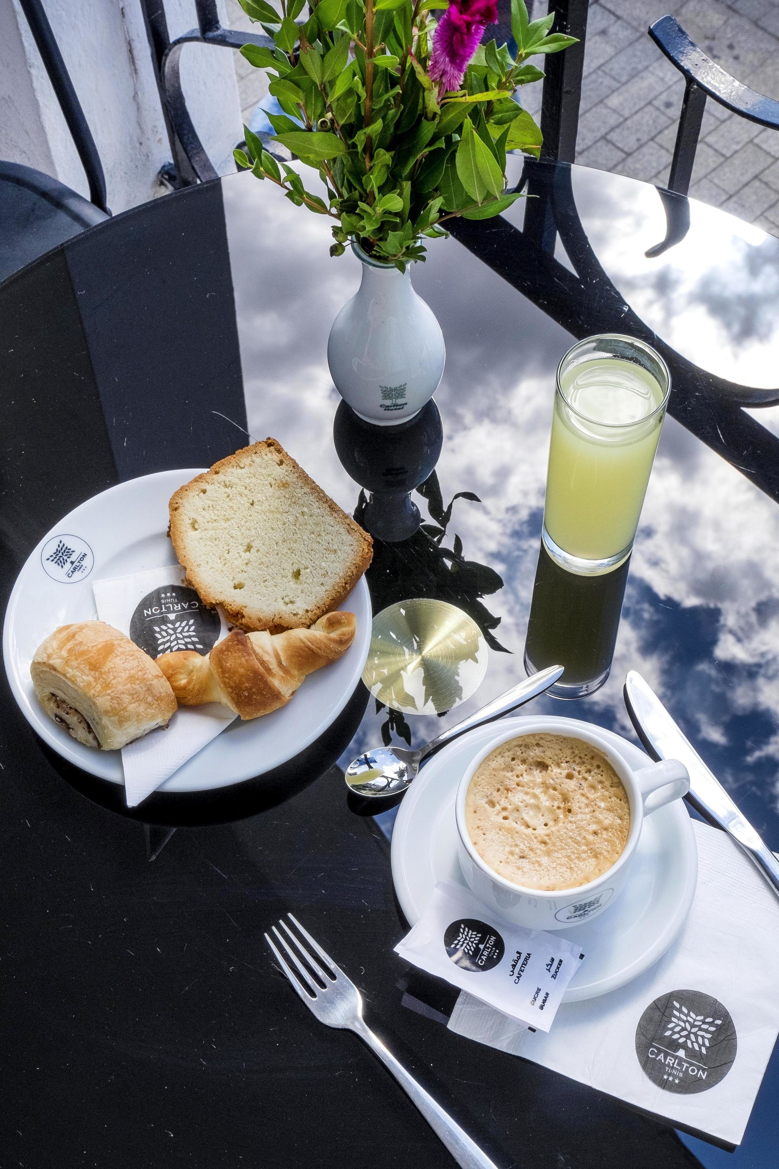 A table with a plate of food, a glass of juice, and a cup of coffee.
