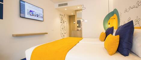 A hotel room with a bed, a mounted TV, and a mirror.