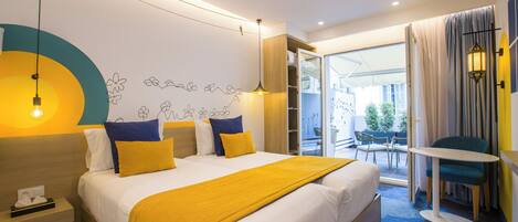 A hotel room with a bed, bedside table, lamp, and a view of the outdoors.