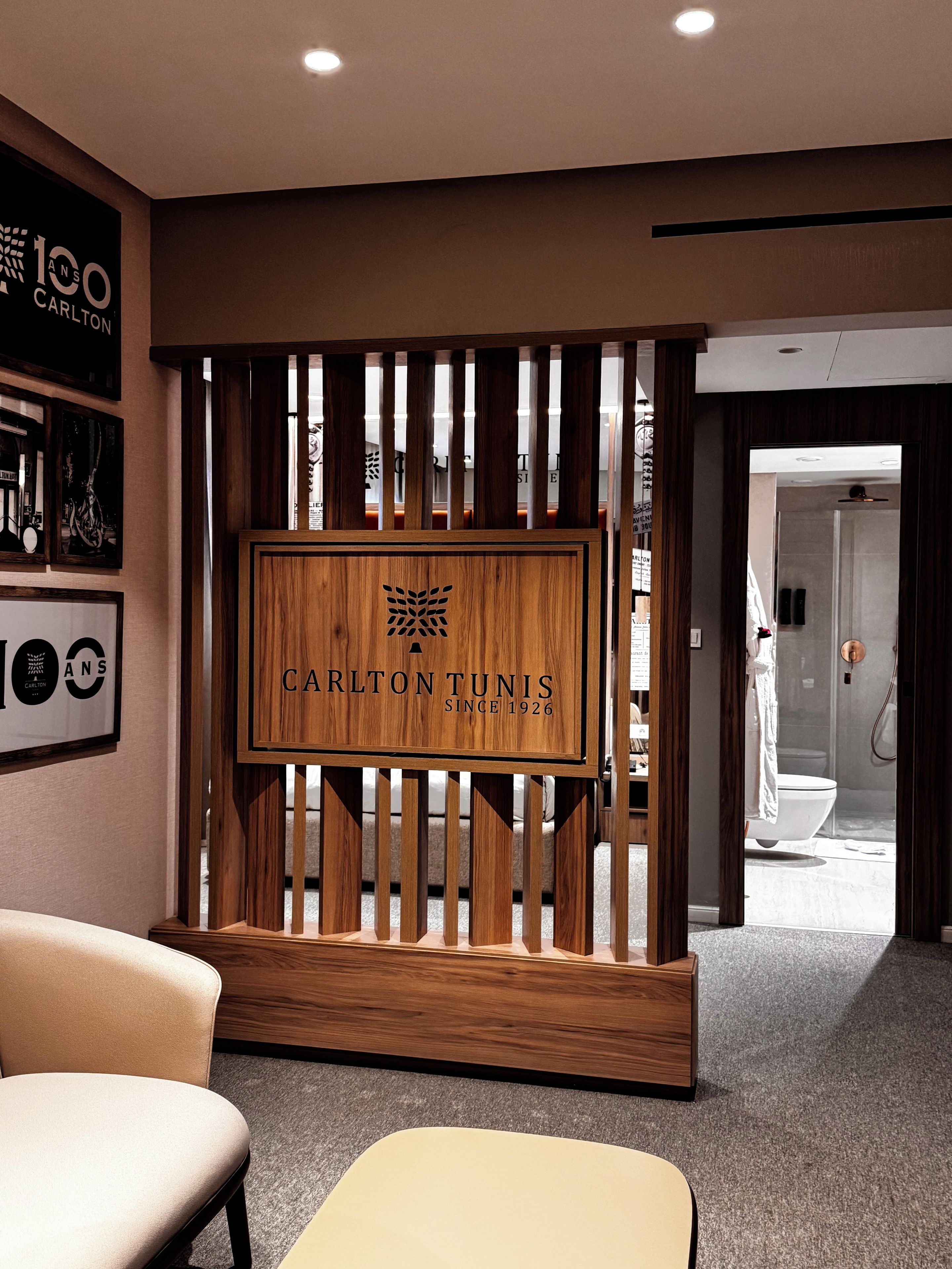 A reception area with a wooden partition displaying 'Carlton Tunis' and a framed '100 years' sign.