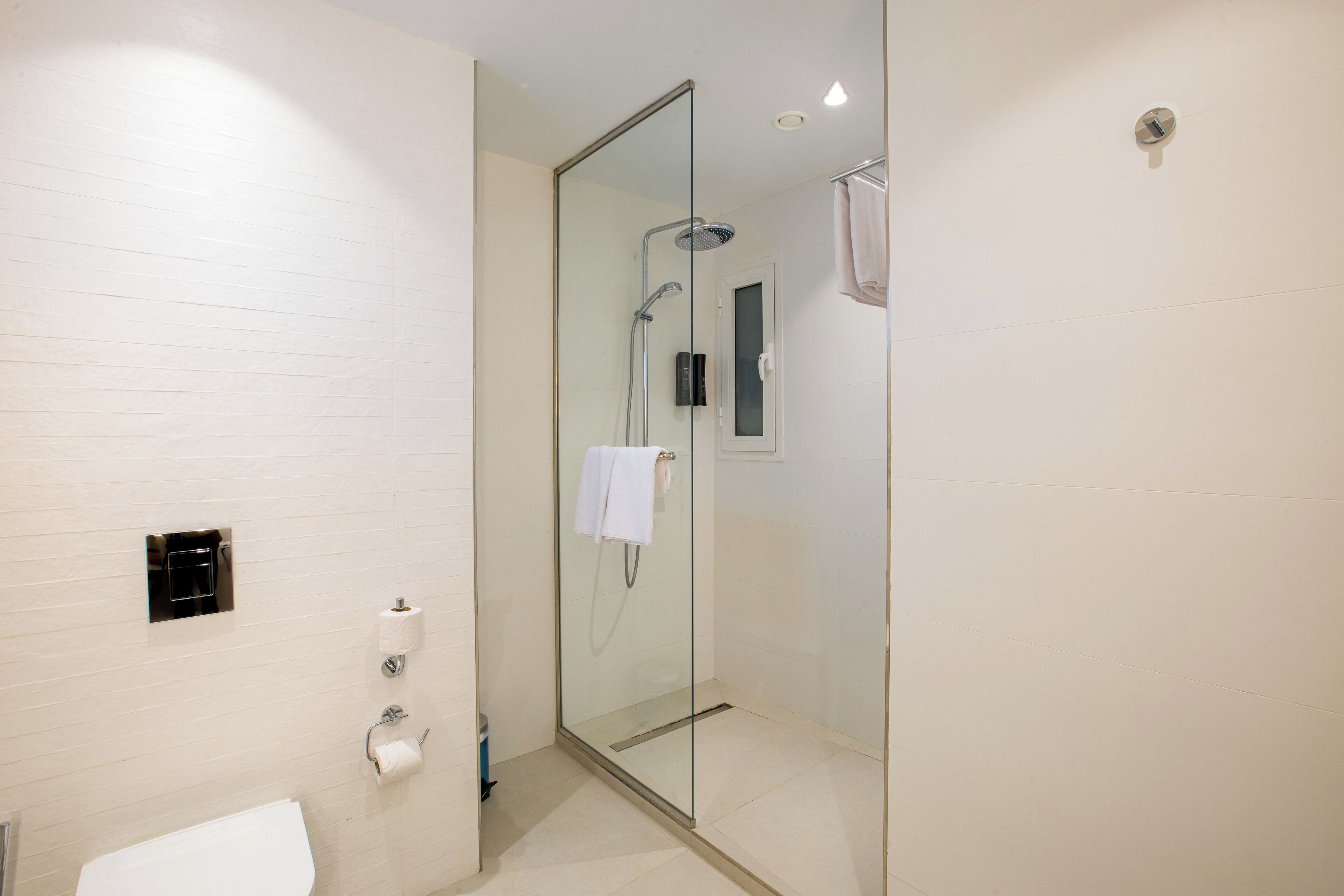 Un baño moderno con ducha de vidrio, inodoro y toallero.