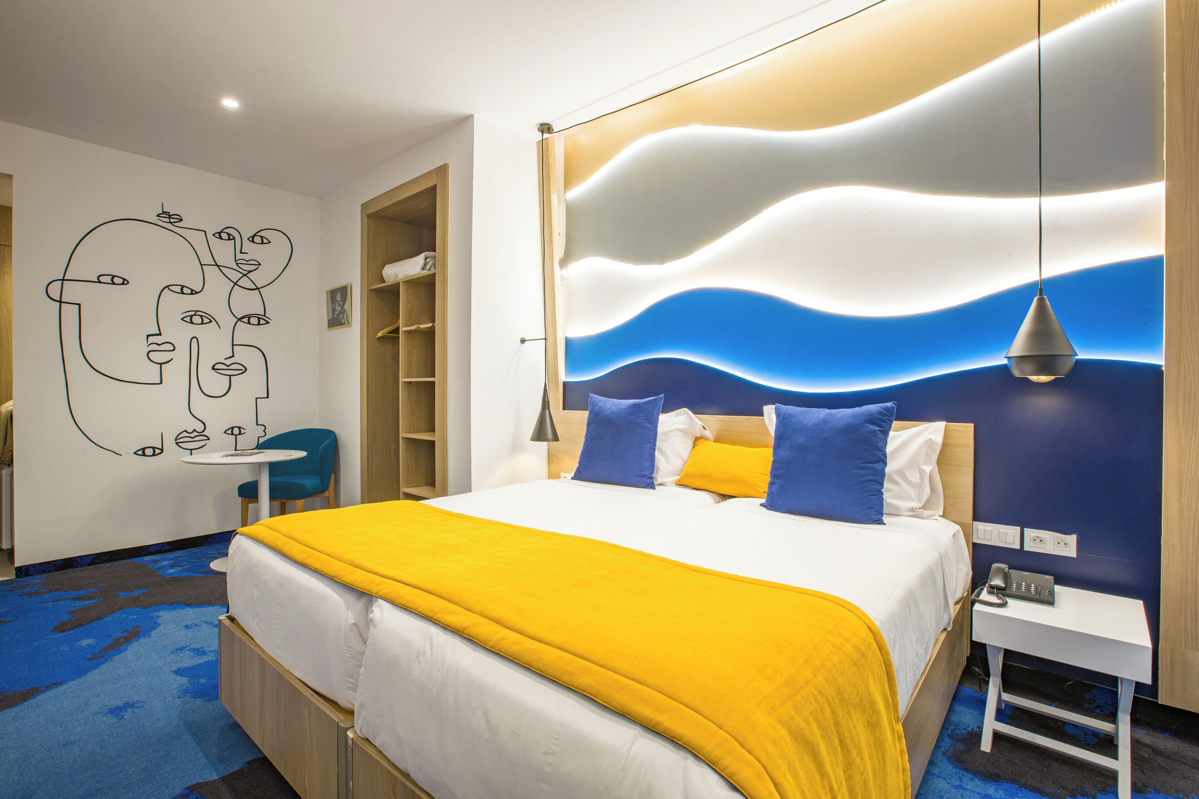 A modern hotel room with a bed, bedside table, and a wall with a wavy pattern.