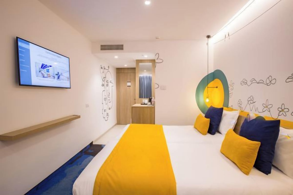 Una habitación de hotel moderna con una cama grande, un televisor y un escritorio con una silla.