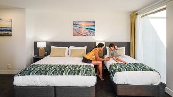 Una habitación de hotel con dos camas, una mesita de noche con lámpara y un cuadro en la pared.