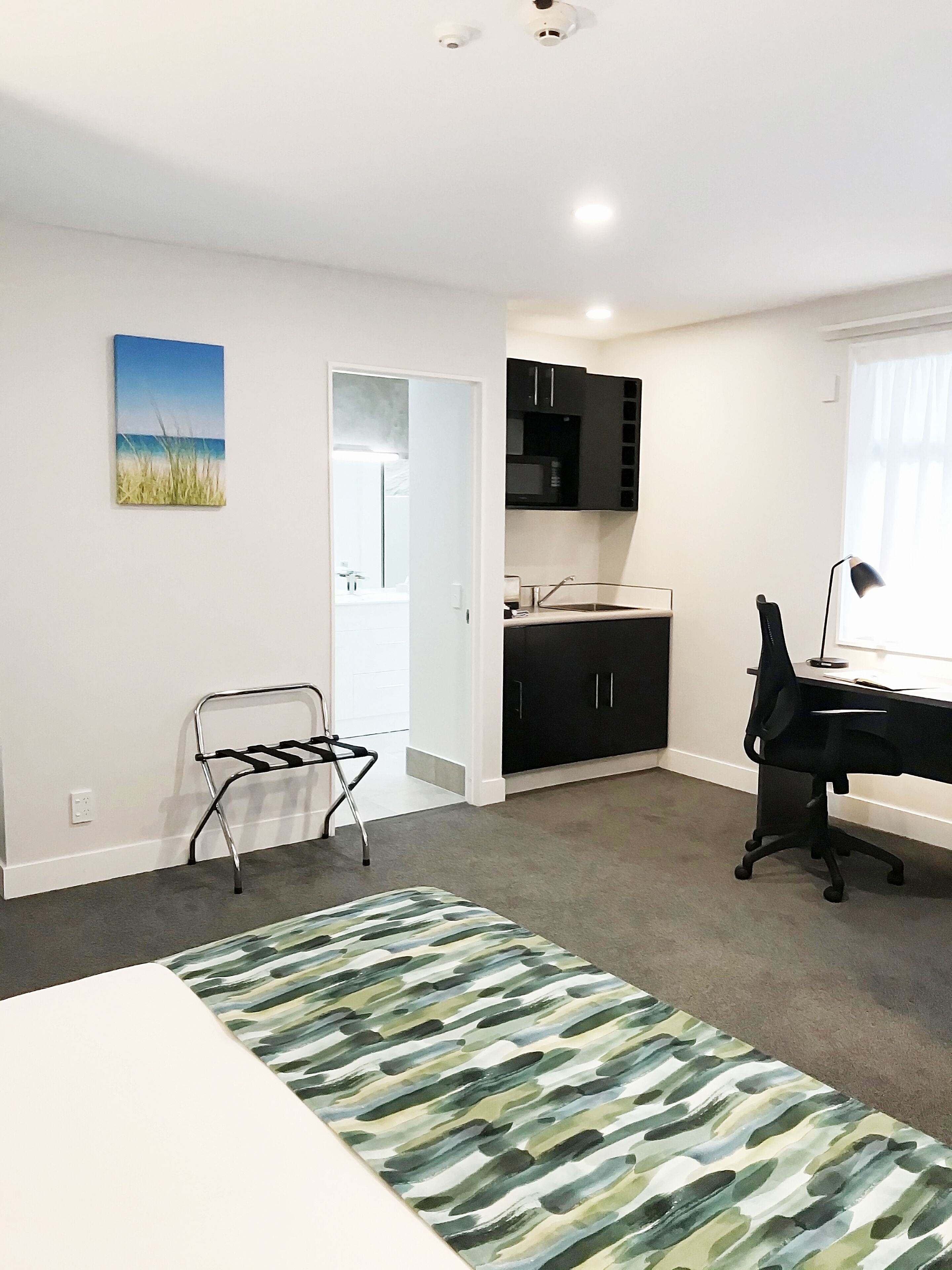 A modern room with a desk, office chair, and a view of the kitchen.