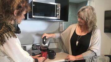 Una cocina con microondas, cafetera y una taza roja sobre la encimera.