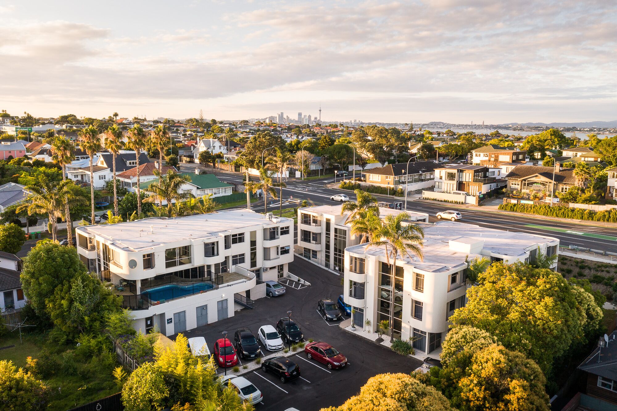 A multi-story parking structure with a pool, surrounded by residential buildings and palm trees.