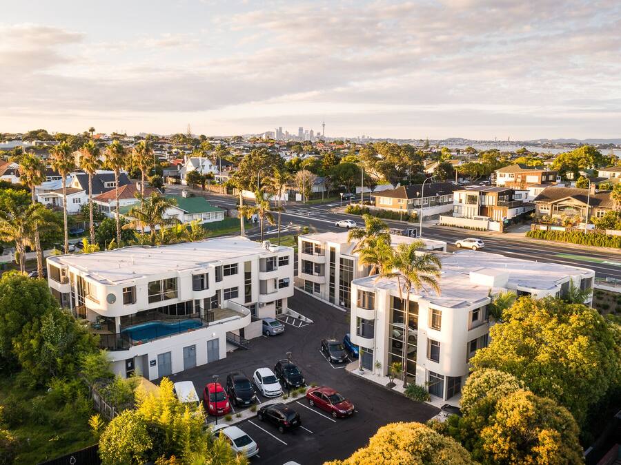 A multi-story parking structure with a pool, surrounded by residential buildings and palm trees.