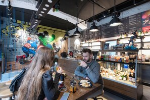 A bar area with a counter, seating, and a menu board. - Numa Prague Root (Prague)