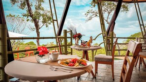 Un comedor con una mesa preparada para dos personas, un florero con flores y una vista panorámica del océano.