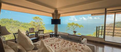 A bedroom with a large window overlooking a scenic view.