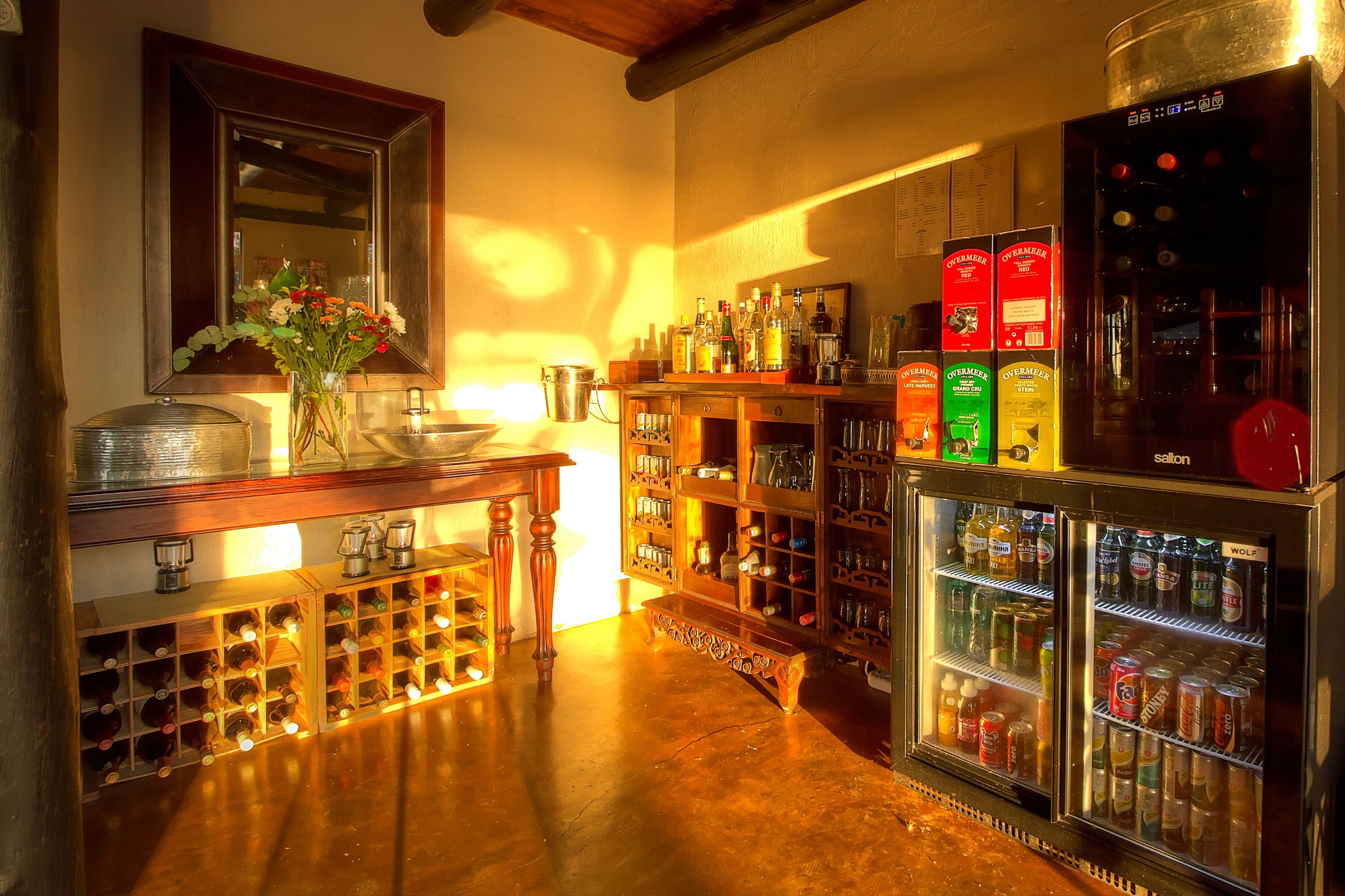 A bar area with a wine rack, shelves of liquor bottles, and a refrigerator stocked with beverages.