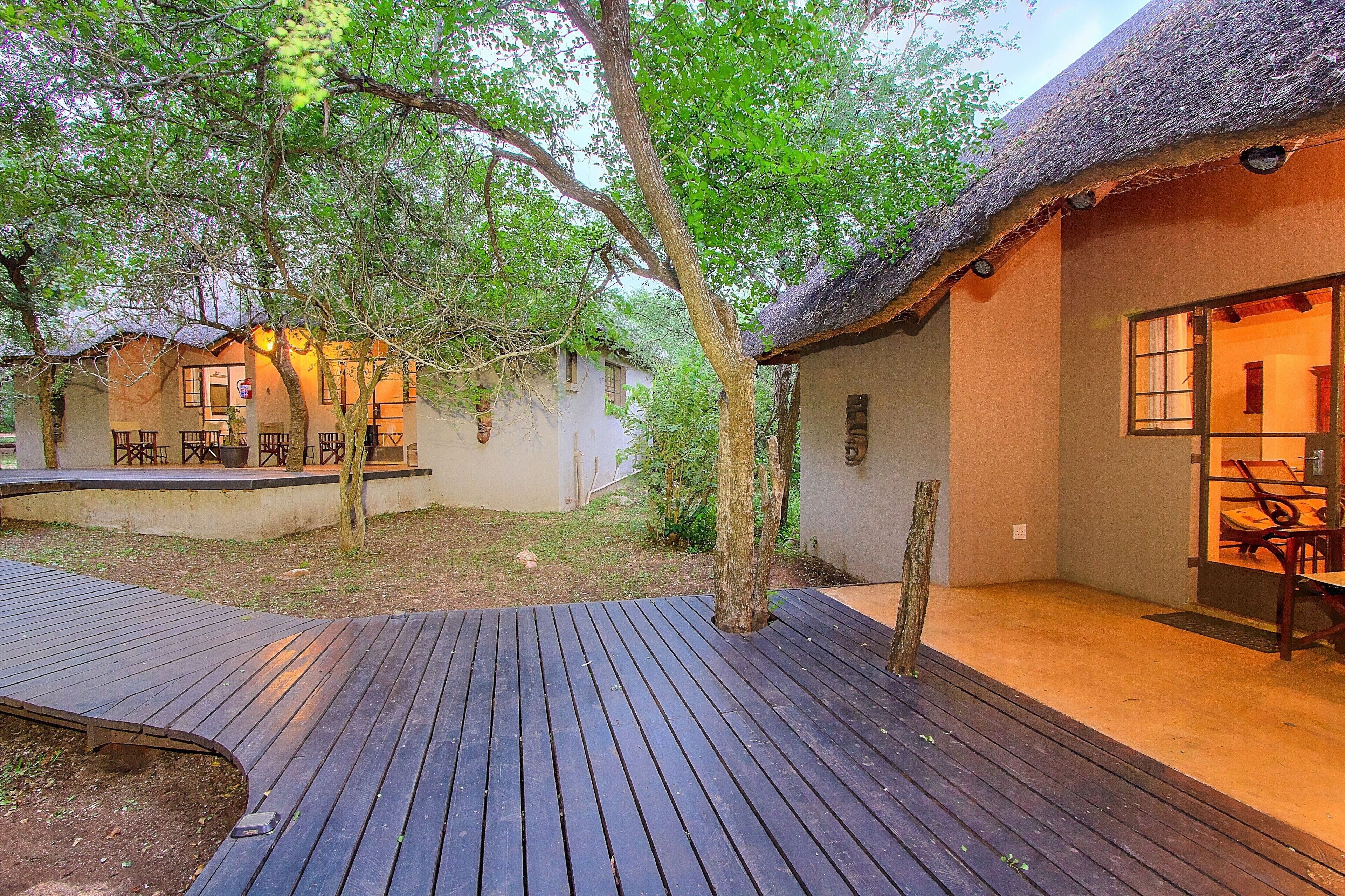 A thatched-roof building with a wooden deck and outdoor seating area.