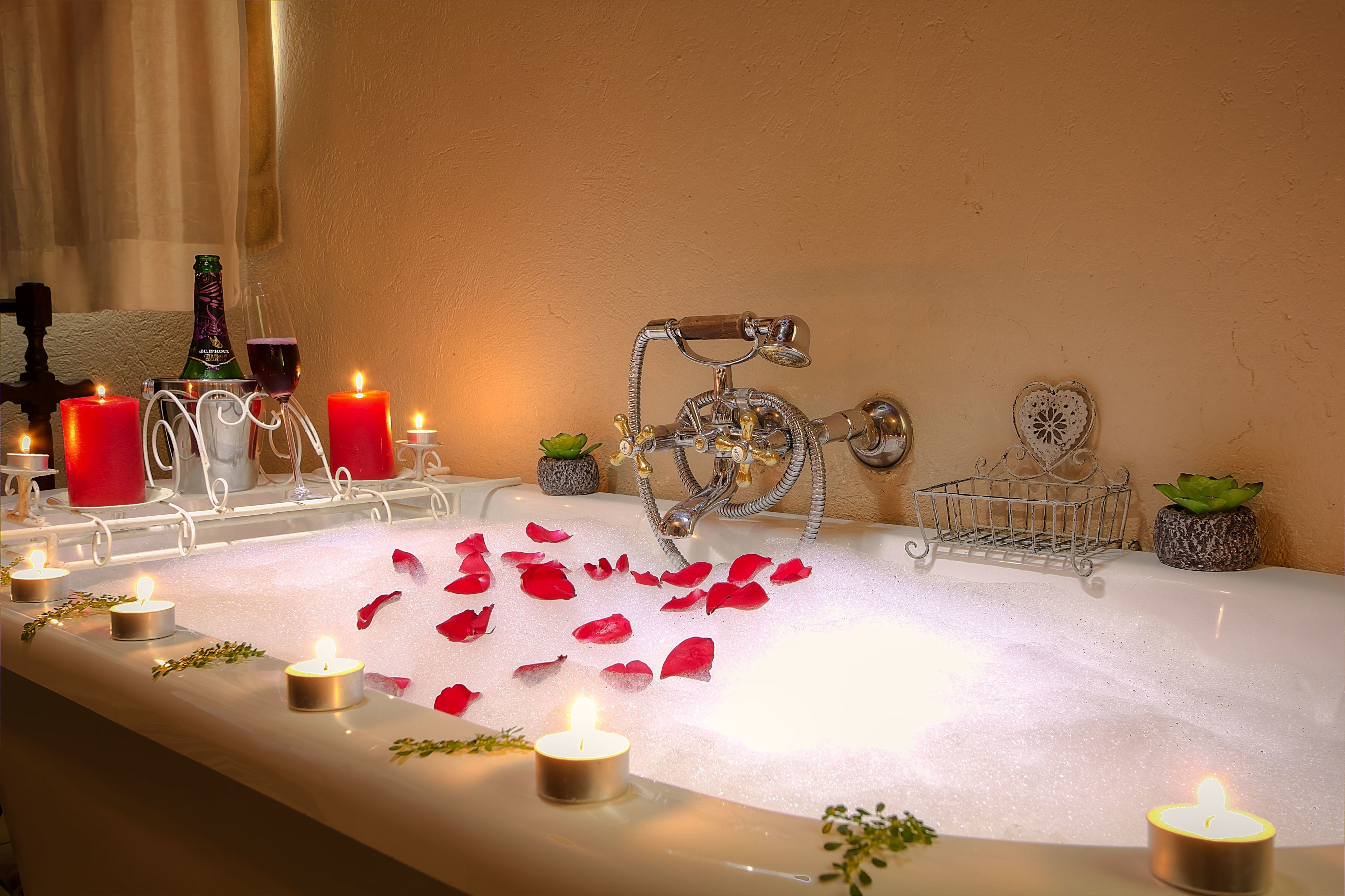 A bathtub with candles, rose petals, and a bottle of champagne.