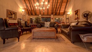 Un salon spacieux avec des canapés en cuir, une table basse en bois et un plafond haut avec des poutres apparentes.