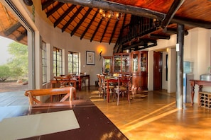 A spacious dining area with wooden furniture and a high ceiling.