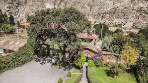 Un patio con una fuente, rodeado de jardines y árboles bien cuidados, con edificios al fondo.