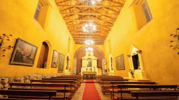 Interior de una iglesia con bancas de madera, un pasillo con alfombra roja y un altar central.