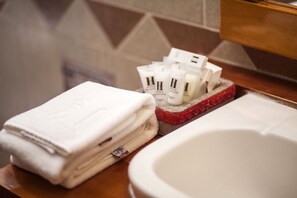 Un baño con una pila de toallas dobladas, una bandeja con artículos de tocador y una bañera.