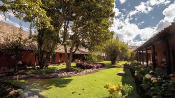 Un patio con césped, árboles y un edificio con tejado de baldosas.