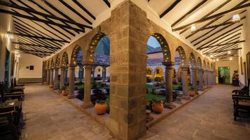 Un patio con columnas de piedra, arcos y plantas en macetas.