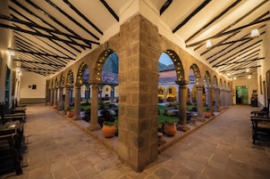 A courtyard with stone columns, arches, and potted plants.