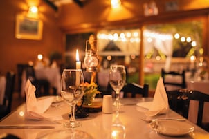 A dining table set with wine glasses, a candle, and a vase with flowers.