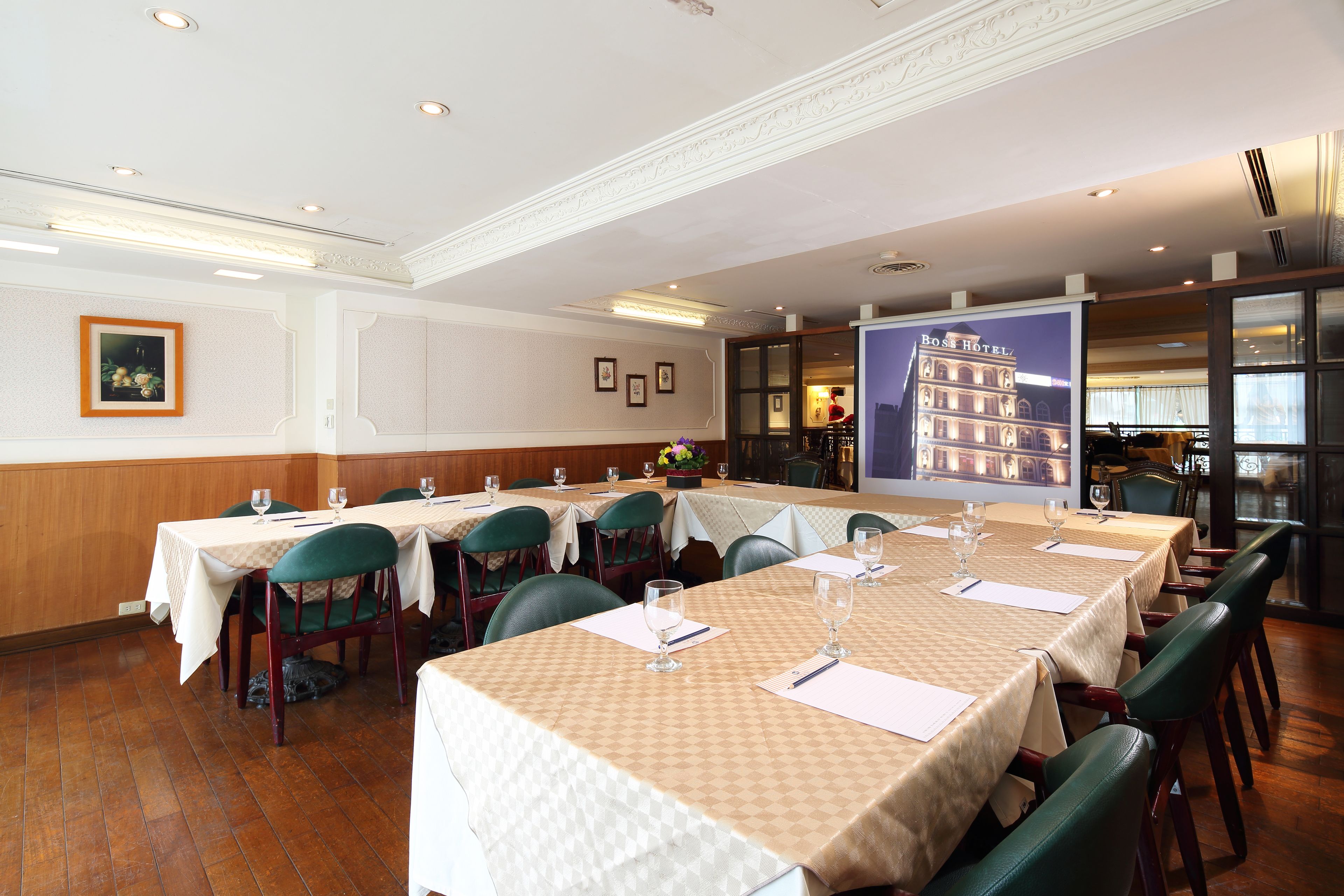 A conference room with multiple tables set for meetings, equipped with chairs, tables, and presentation screens.