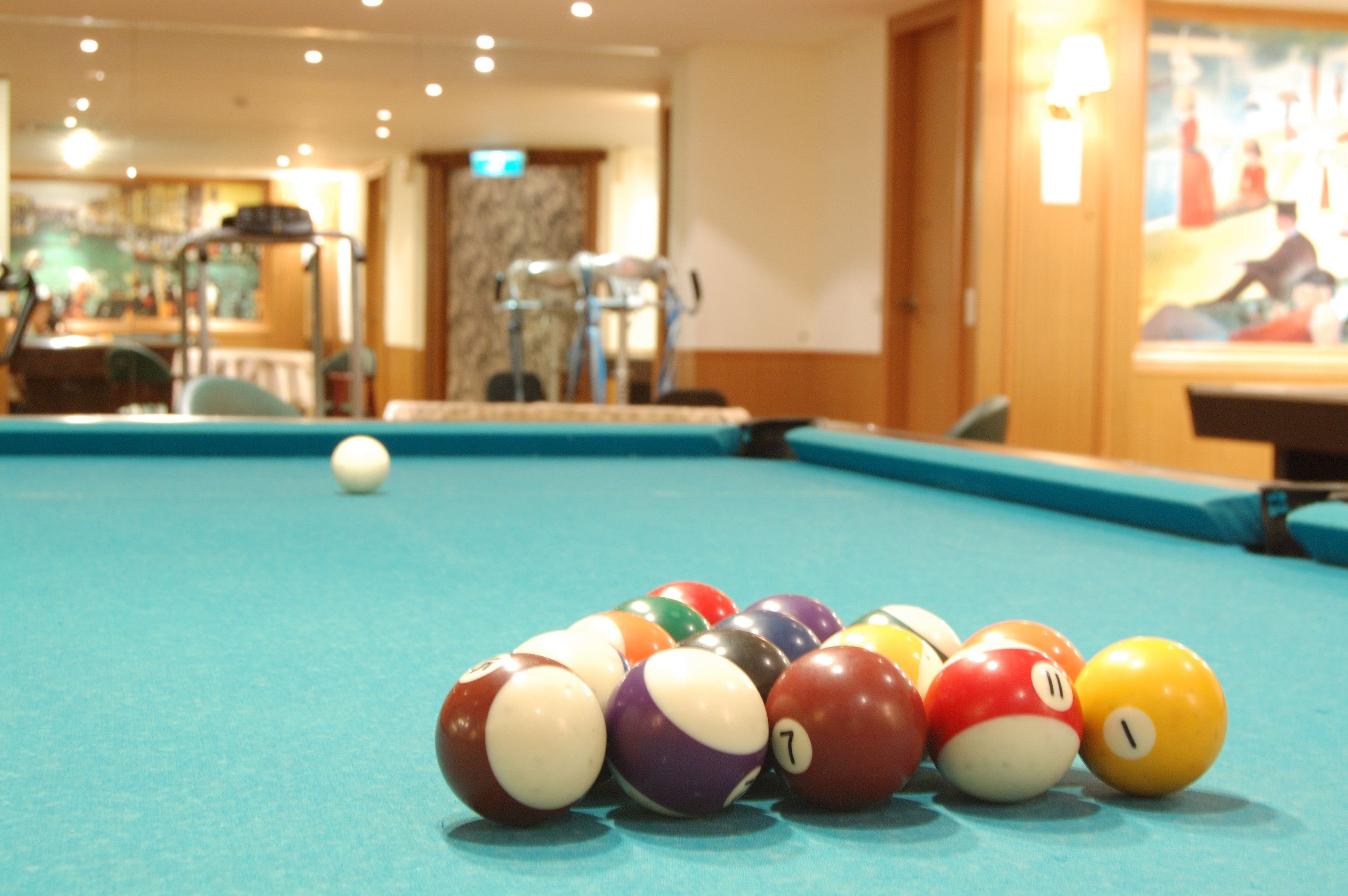 Une table de billard avec des billes et une boule blanche, le tout posé sur un tapis bleu.
