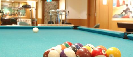 Une table de billard avec des billes et une boule blanche, le tout posé sur un tapis bleu.