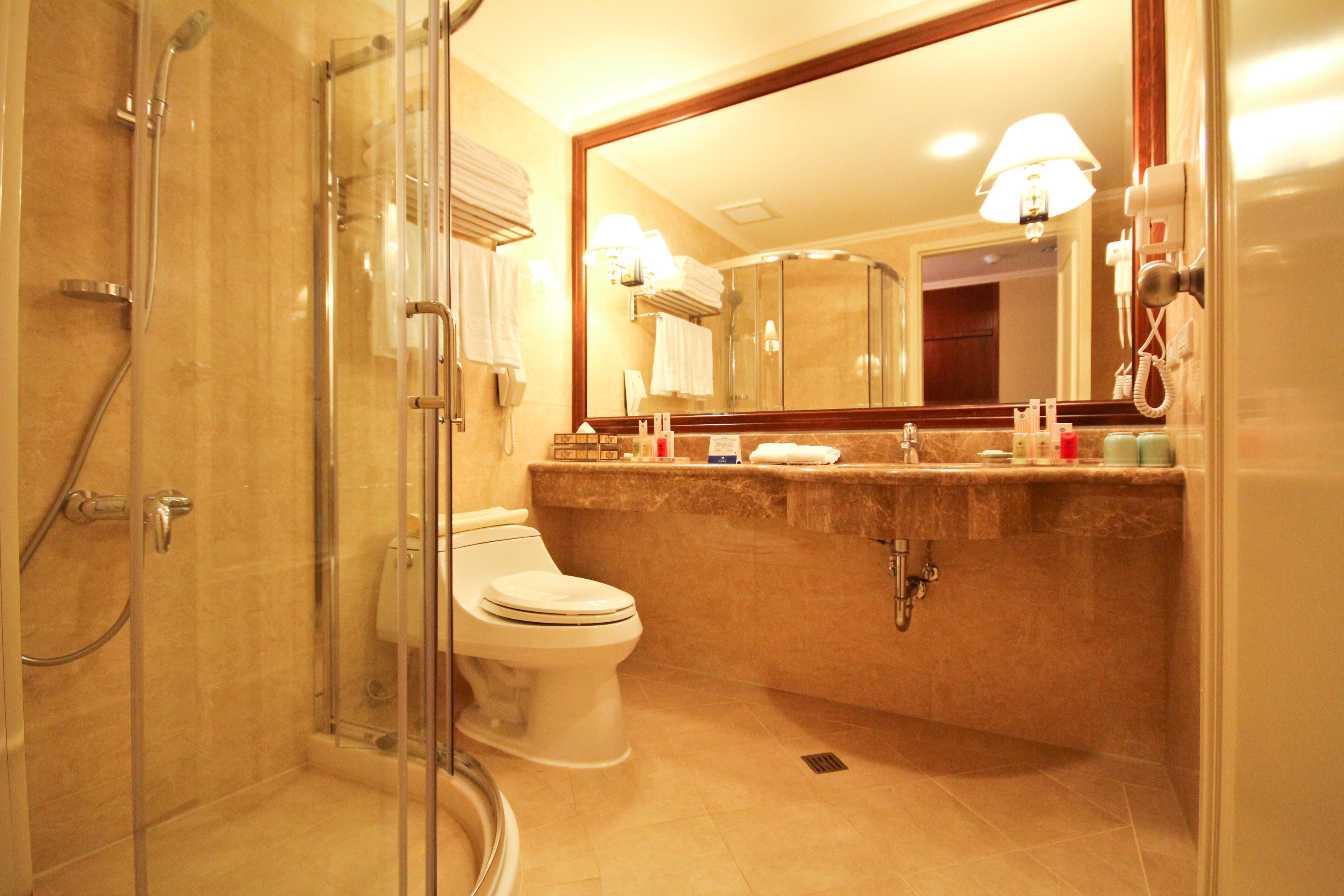 Une salle de bain moderne avec une douche à parois de verre, des toilettes, un lavabo avec un miroir et un meuble-lavabo avec des articles de toilette.