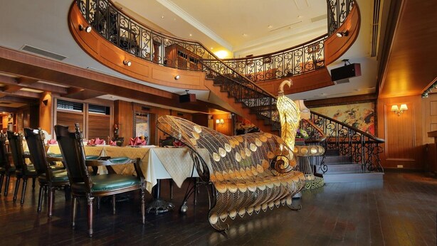 Un lobby de hotel elegante con una escalera espiral, barandales ornamentados y un sofá decorativo grande.