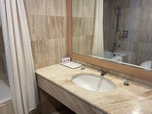 A bathroom with a marble sink, a mirror, and a shower area.