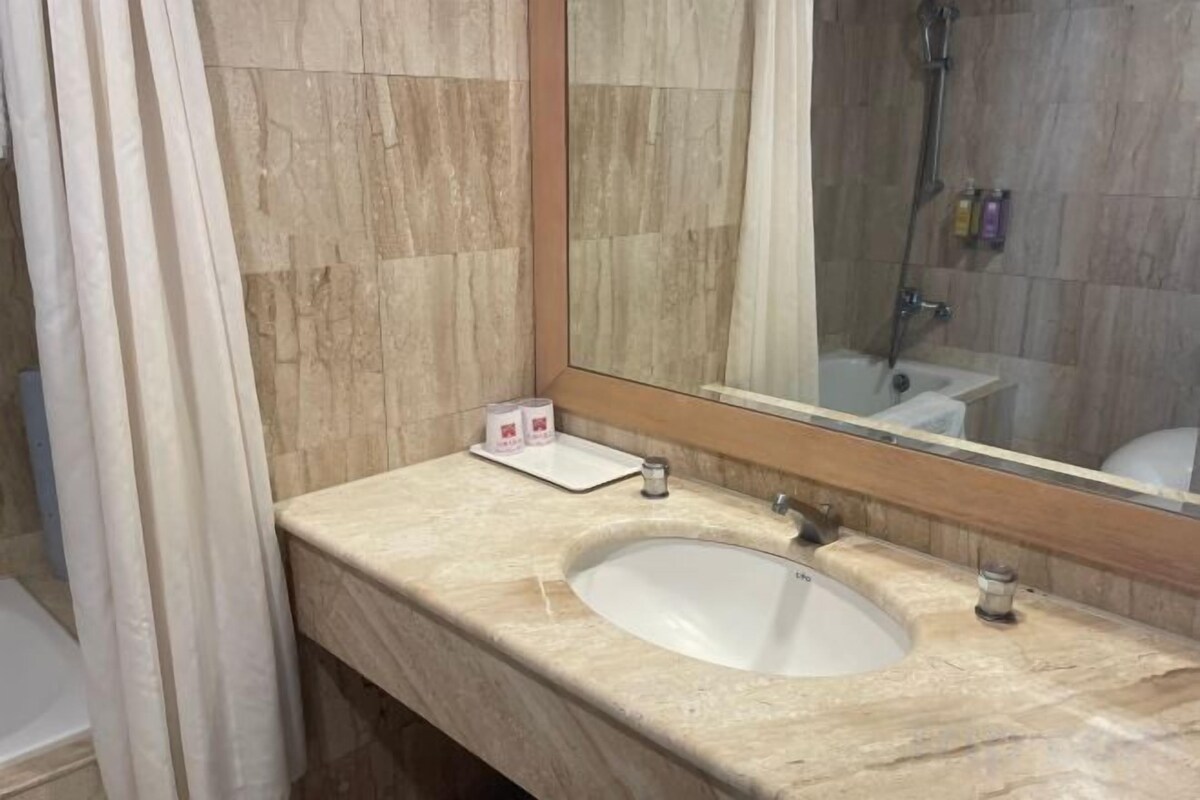 A bathroom with a marble sink, a mirror, and a shower.