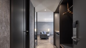 A modern hotel corridor with a sofa set in the background, a hanging light fixture, and a door on the right. - Lakeshore Hotel Metropolis (Hsinchu)