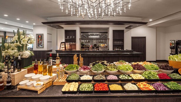 A modern hotel lobby with a central bar area, a chandelier, and a variety of food and drink options. - Lakeshore Hotel Metropolis (Hsinchu)