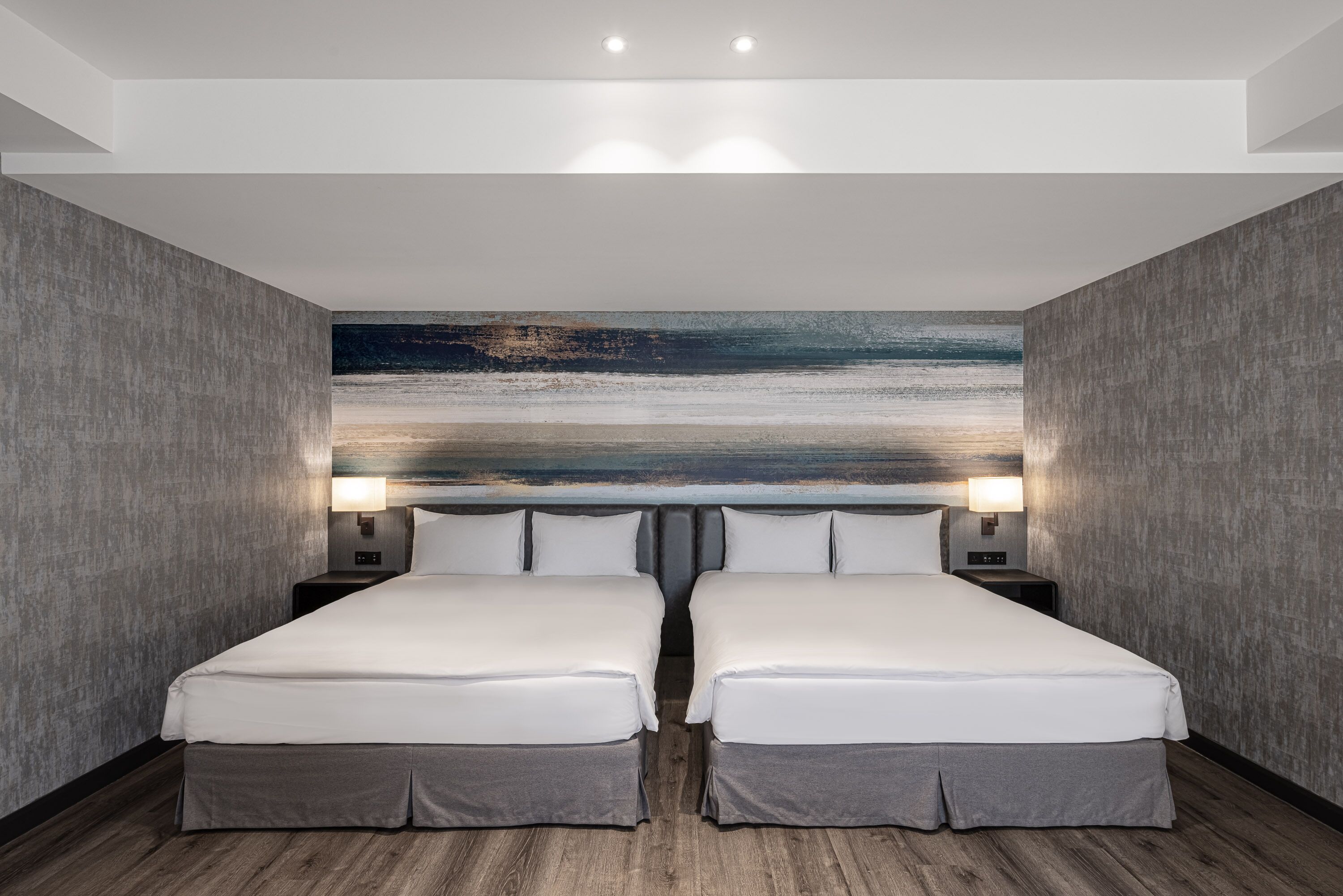 A double room with two beds, a large abstract painting on the wall, and a wooden floor.