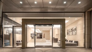 A modern hotel lobby with a glass entrance, a reception desk, and a seating area. - Lakeshore Hotel Metropolis (Hsinchu)