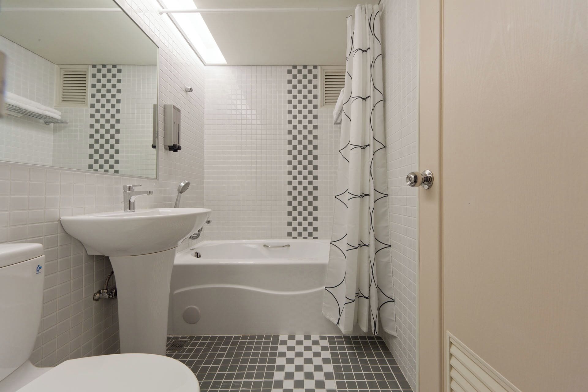 Un baño con lavamanos, inodoro, bañera y cortina de ducha.